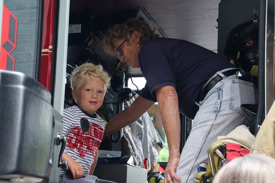 A child is helped to sit inside a fire engine on display