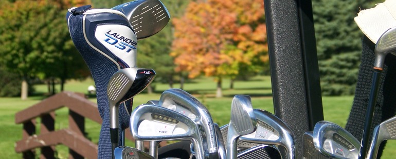 close up of golf club with fall trees in background