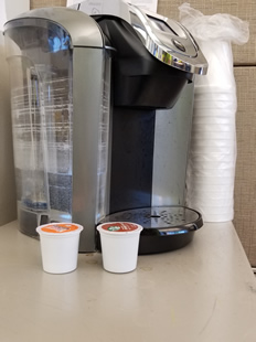 Coffee pods next to single-serving coffee pot. These belong in the trash. Do not put them in the recycling.